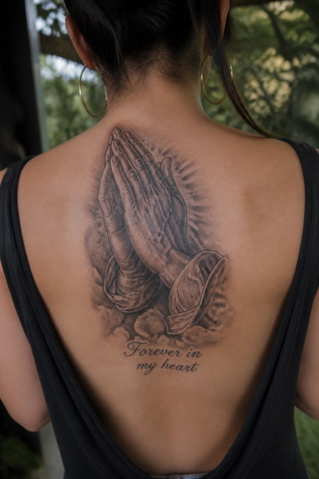 Woman's back in black tank top with praying hands rosary tattoo and