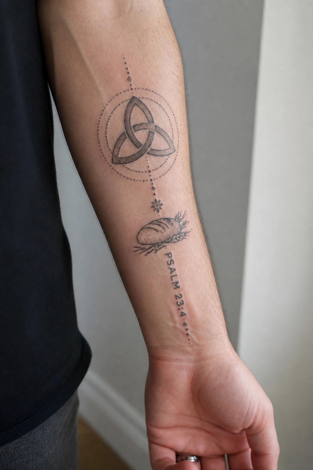 Arm in black sleeve with Triquetra circle tattoo, bread illustration, and Psalm 23:4 text.