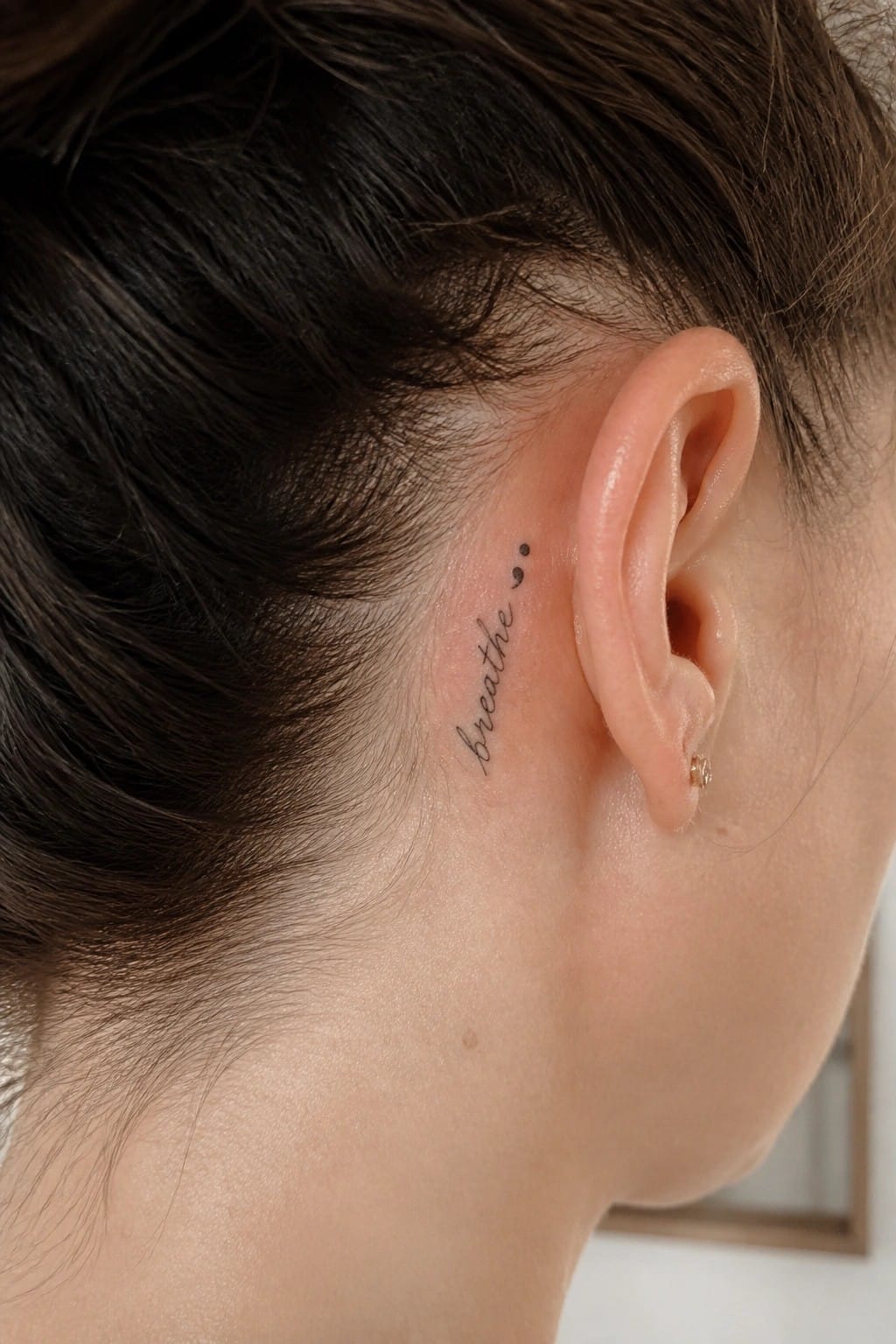 Close-up of dark hair, ear with gold stud, and