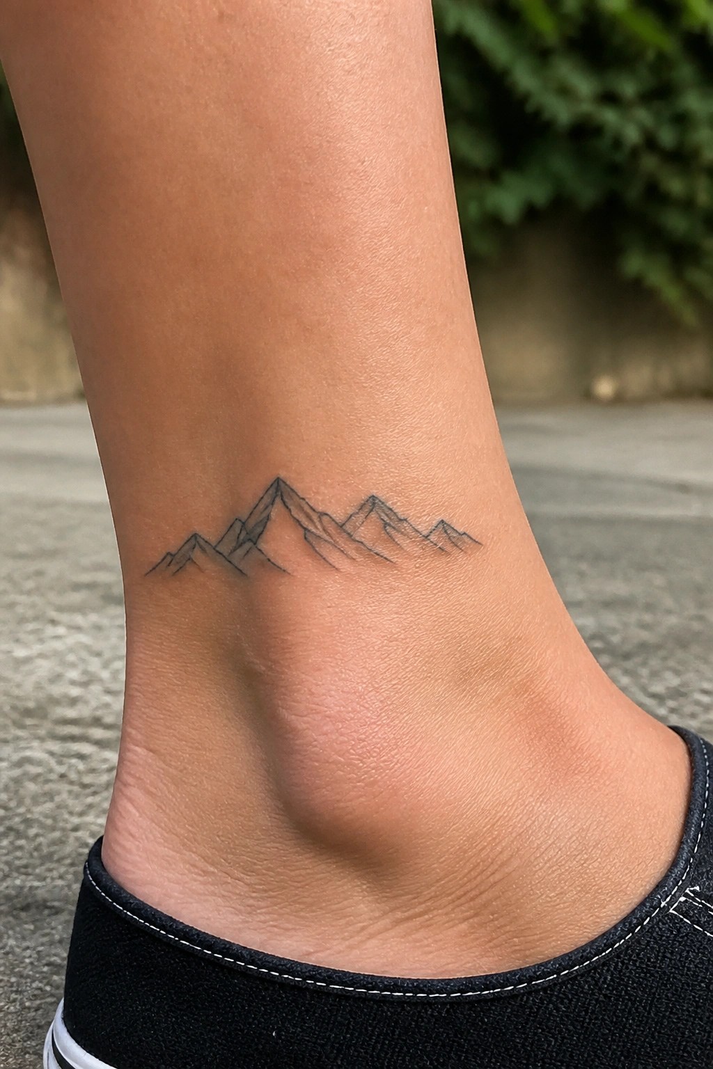 Black mountain range tattoo on ankle above black sneaker