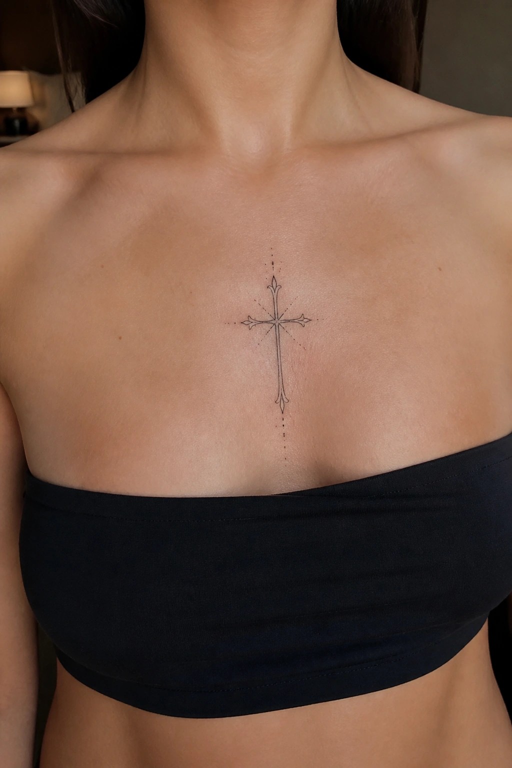 Light-skinned chest with ornate cross tattoo above black strapless top