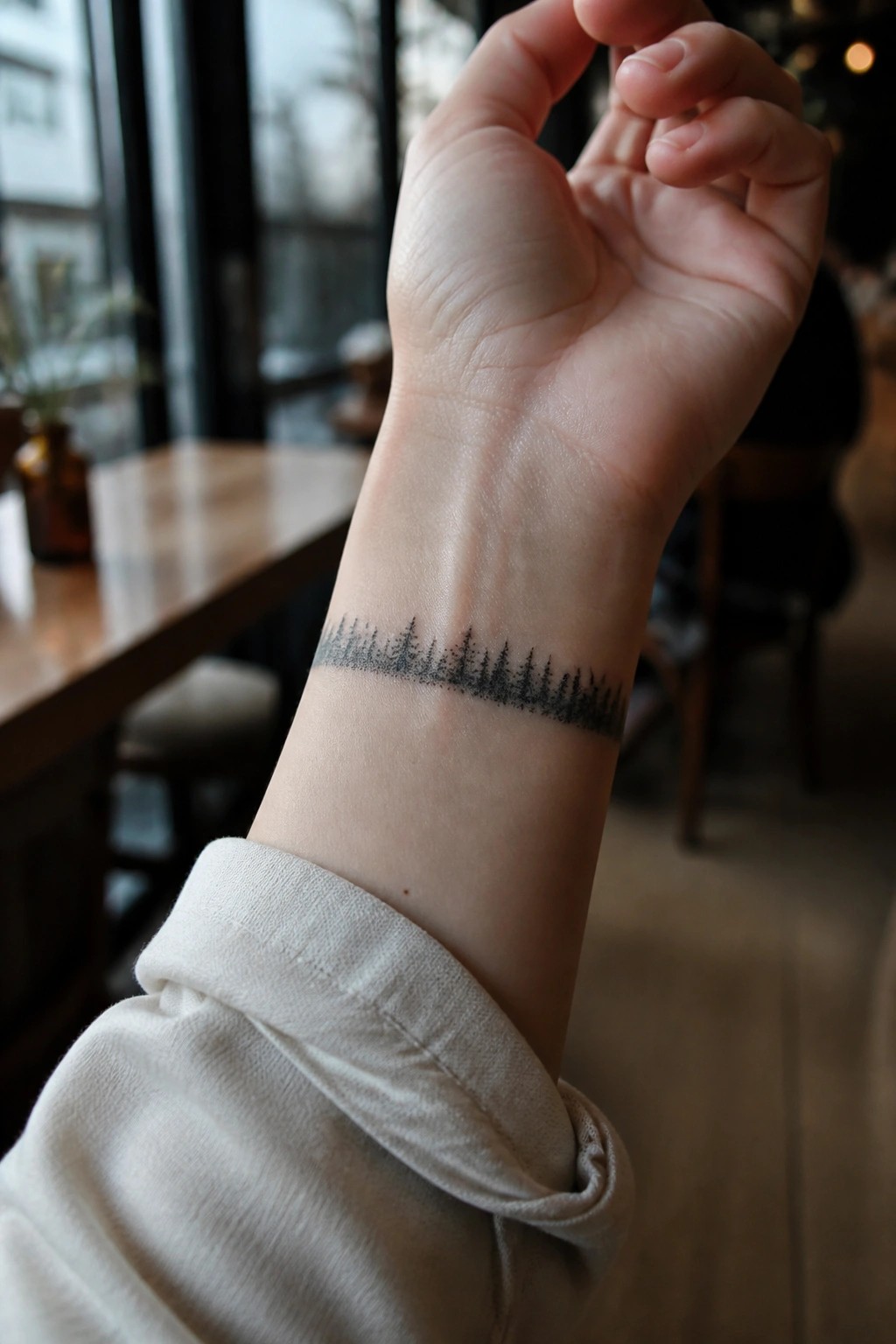 Small black ink forest silhouette tattoo on the inner wrist