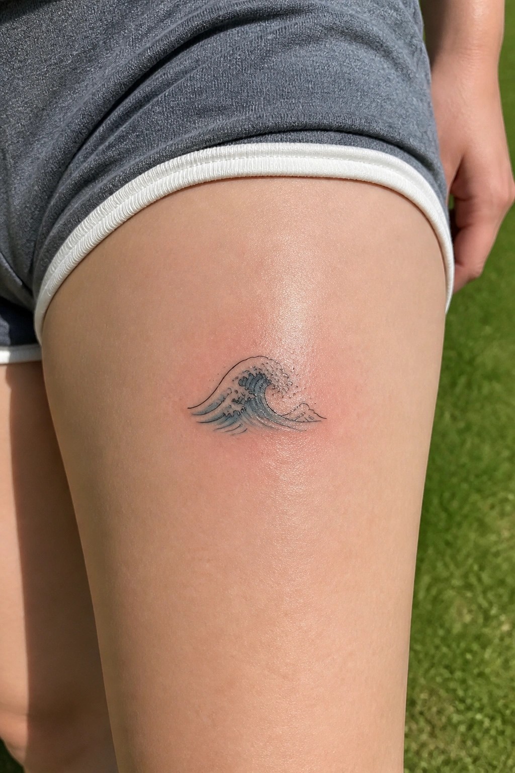 Small fine line wave tattoo on the upper thigh