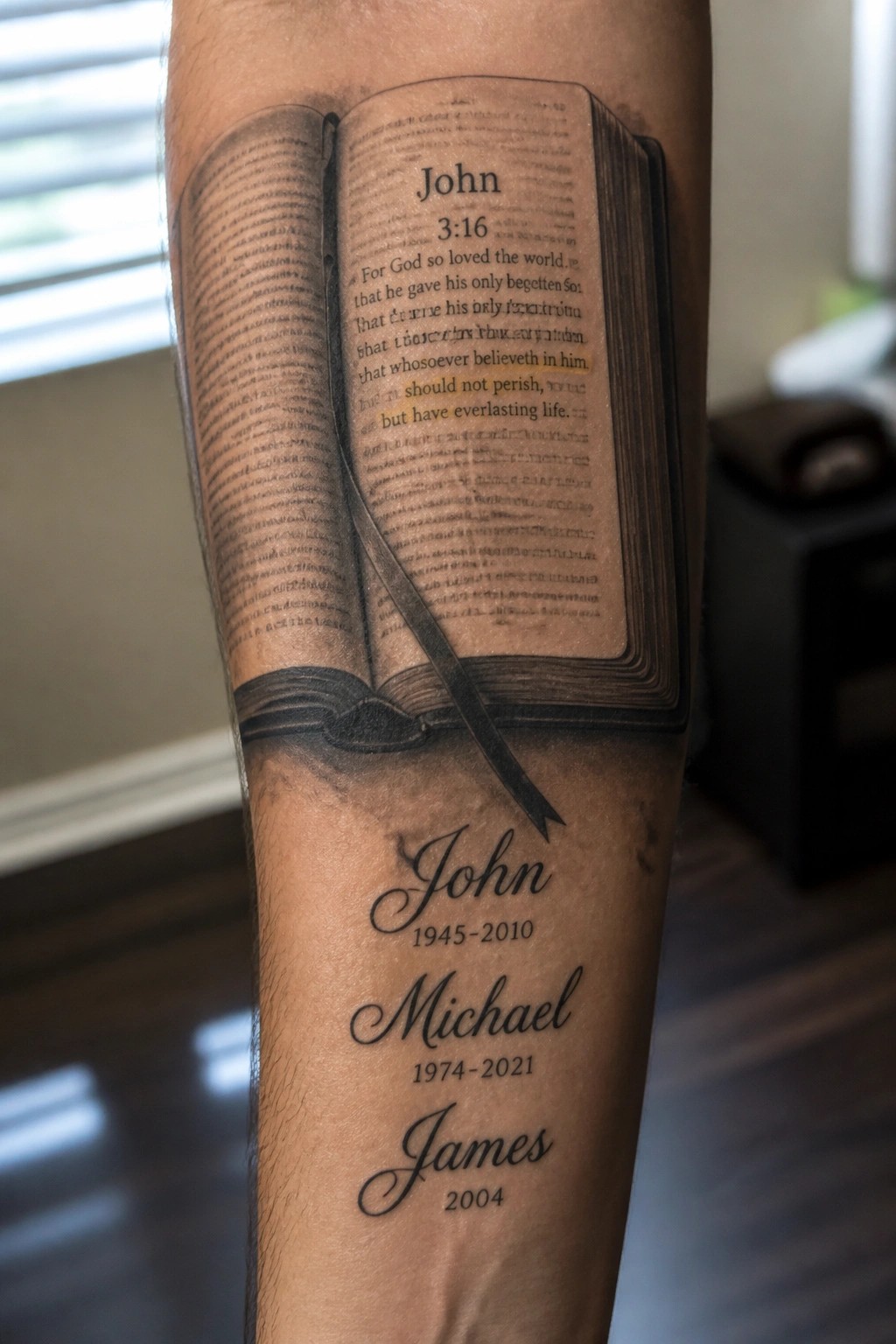 Arm tattoo of open Bible with John 3:16 verse and memorial names below