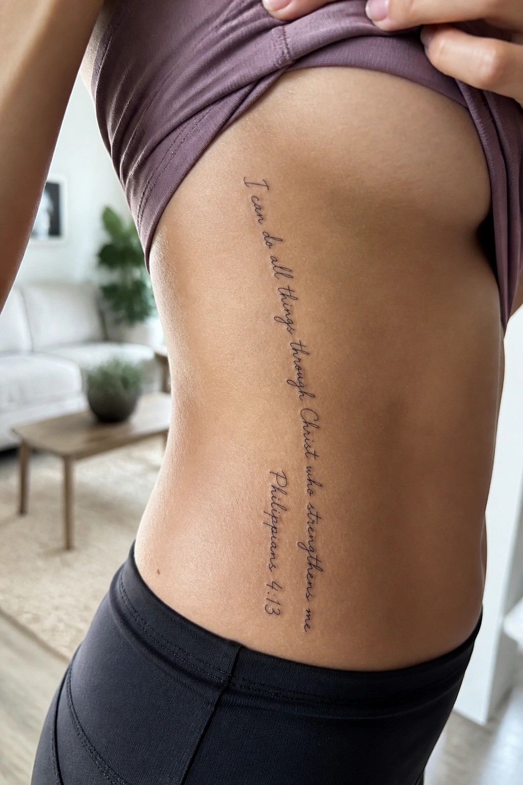 Woman lifts purple top to show Philippians 4:13 tattoo on side