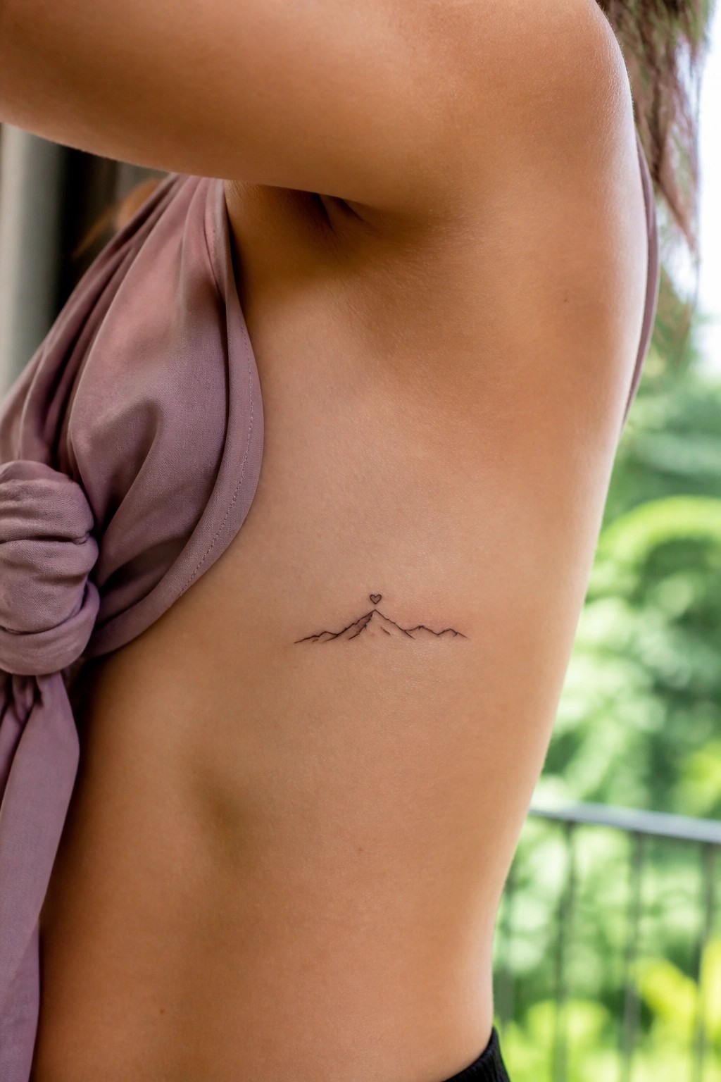 Small mountain tattoo with heart on upper arm, purple knotted sleeveless top