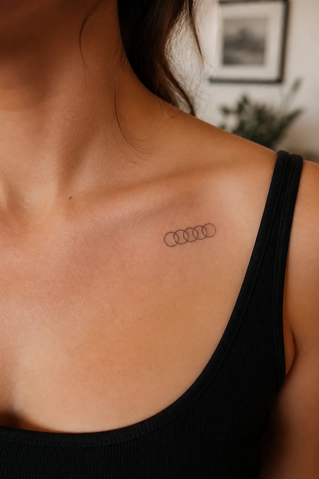 Woman's shoulder with five overlapping circles tattoo on black tank top