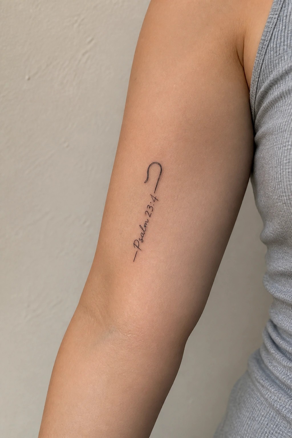 Shepherd's hook tattoo above Psalm 23:4 on upper arm in gray top