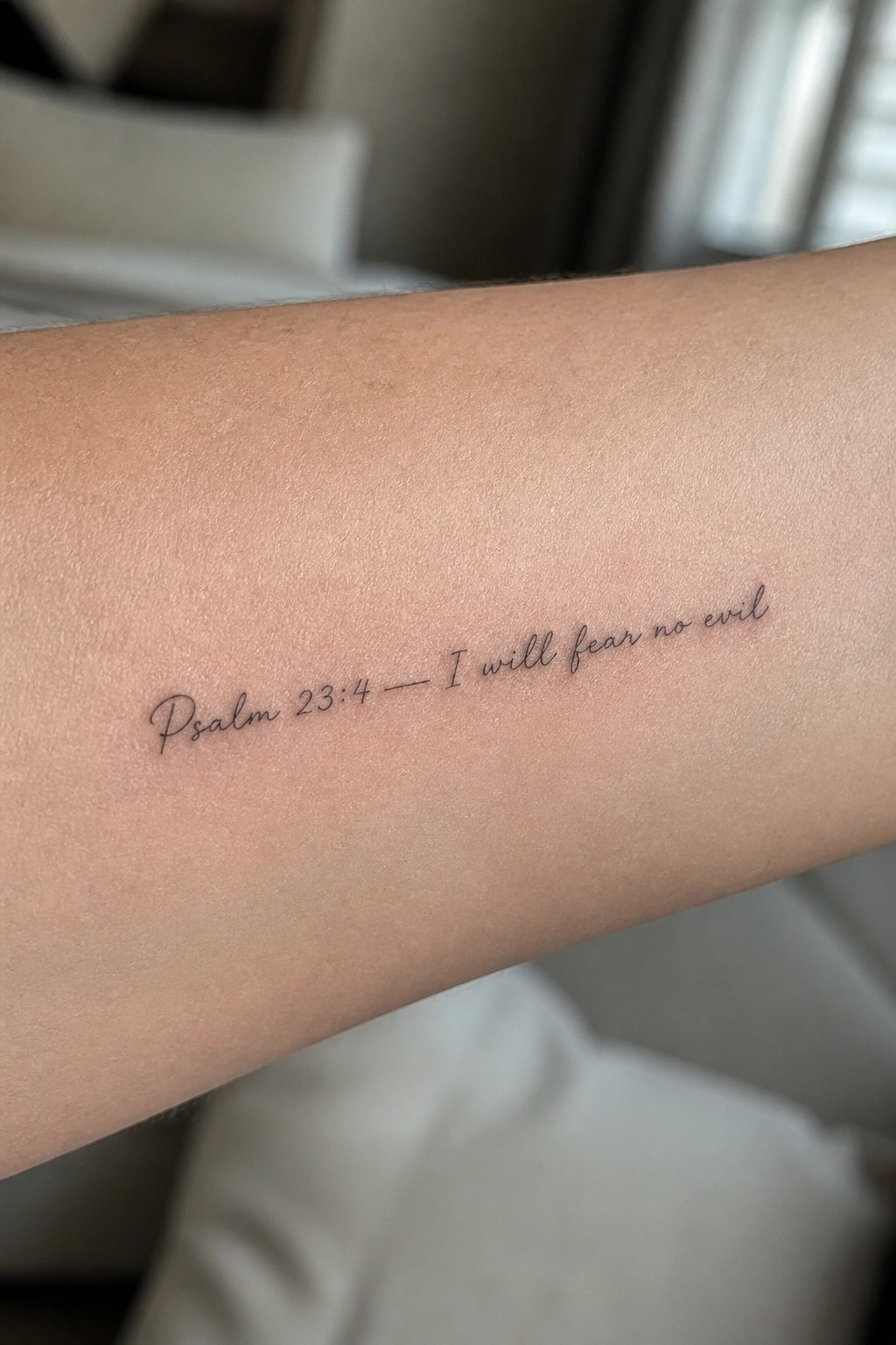 Forearm with black cursive tattoo reading Psalm 23:4 — I will fear no evil