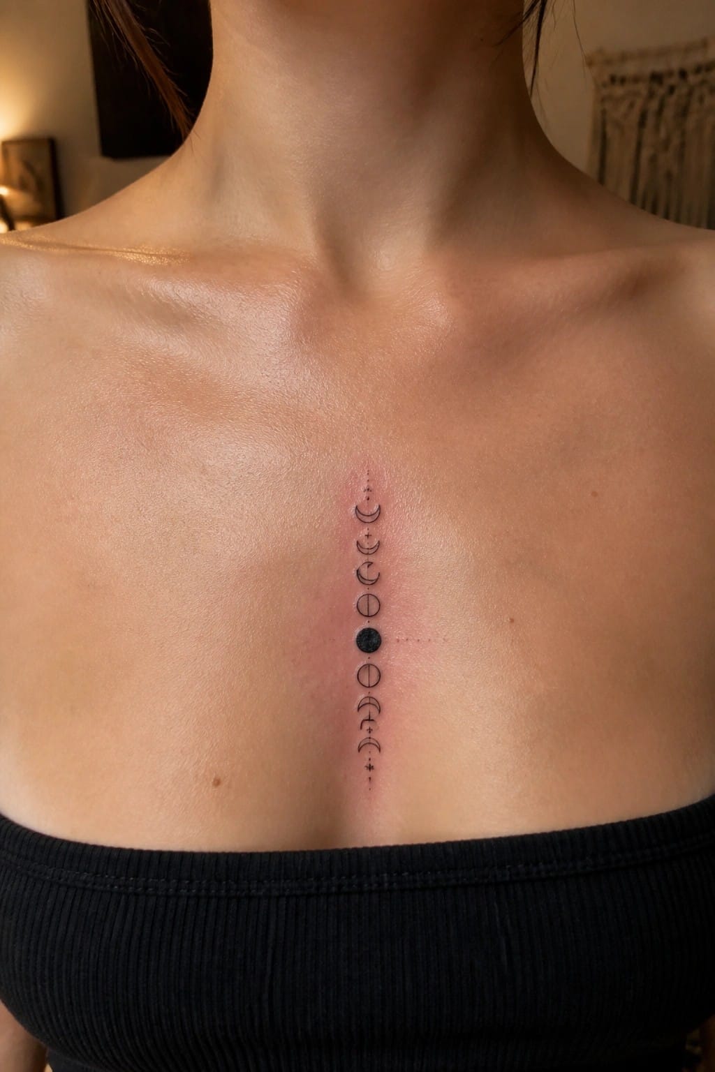 Vertical moon phases tattoo on chest with redness above black top