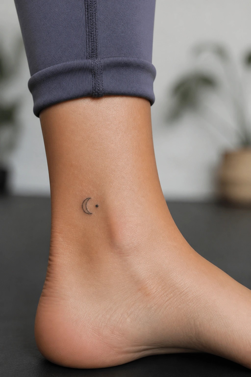 Small crescent moon with a dot tattoo on the ankle in minimalist line style