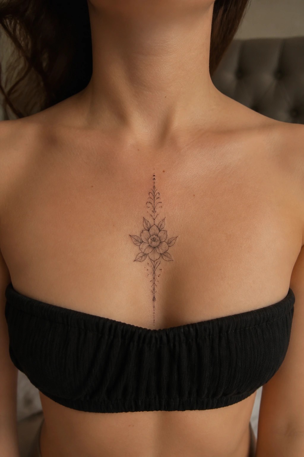 Floral tattoo on sternum above black strapless top on light skin