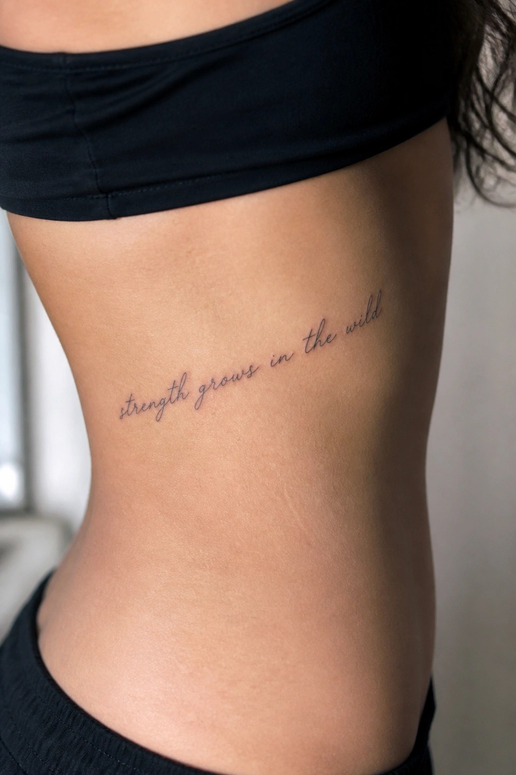 Person in black crop top with cursive tattoo