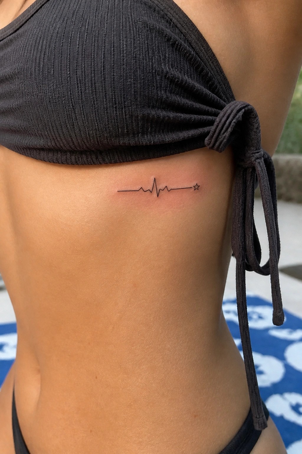 Black bikini top with heartbeat line tattoo and star on side torso