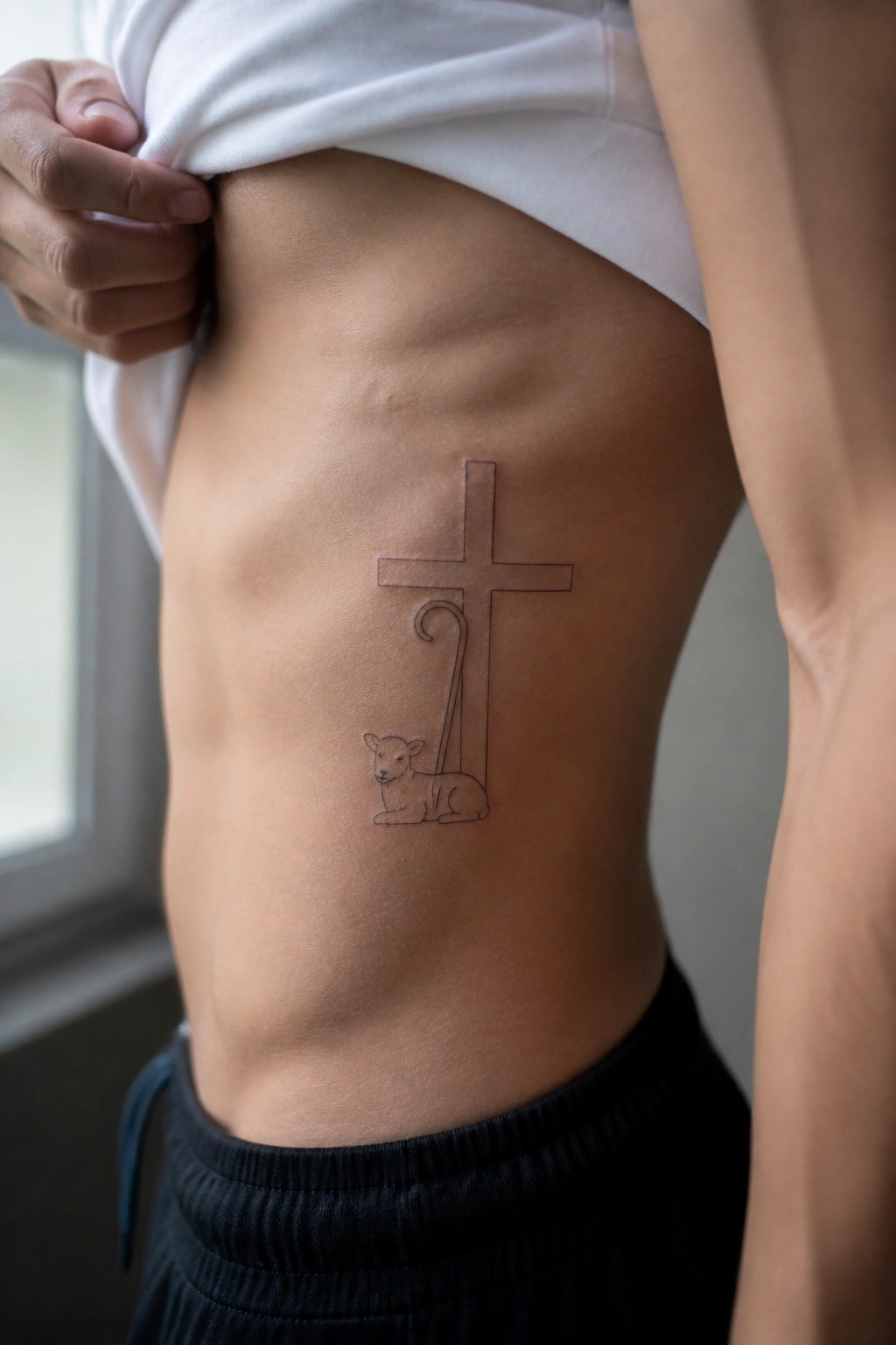 Person lifting white shirt to reveal cross and lamb tattoo on abdomen