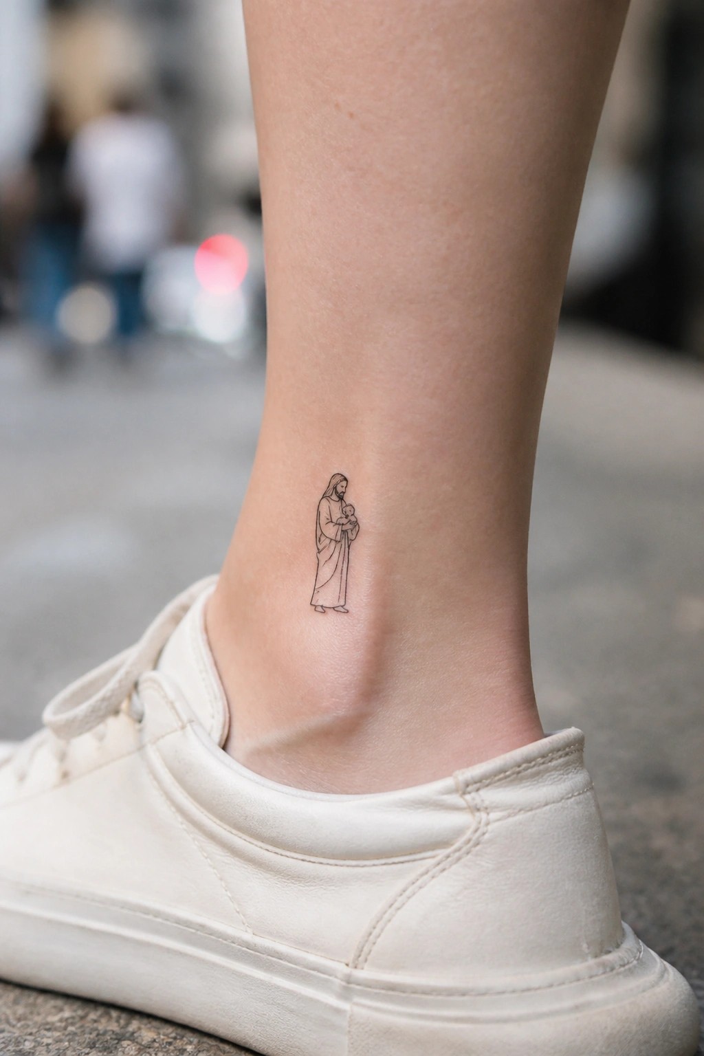 Small black-ink tattoo of Jesus holding child on ankle above white sneaker