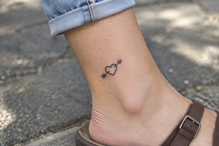 18 Bold Fine Line Symbol Tattoos for Women Featuring Hearts, Stars, and Arrows Fine line heart and arrow tattoo on the ankle