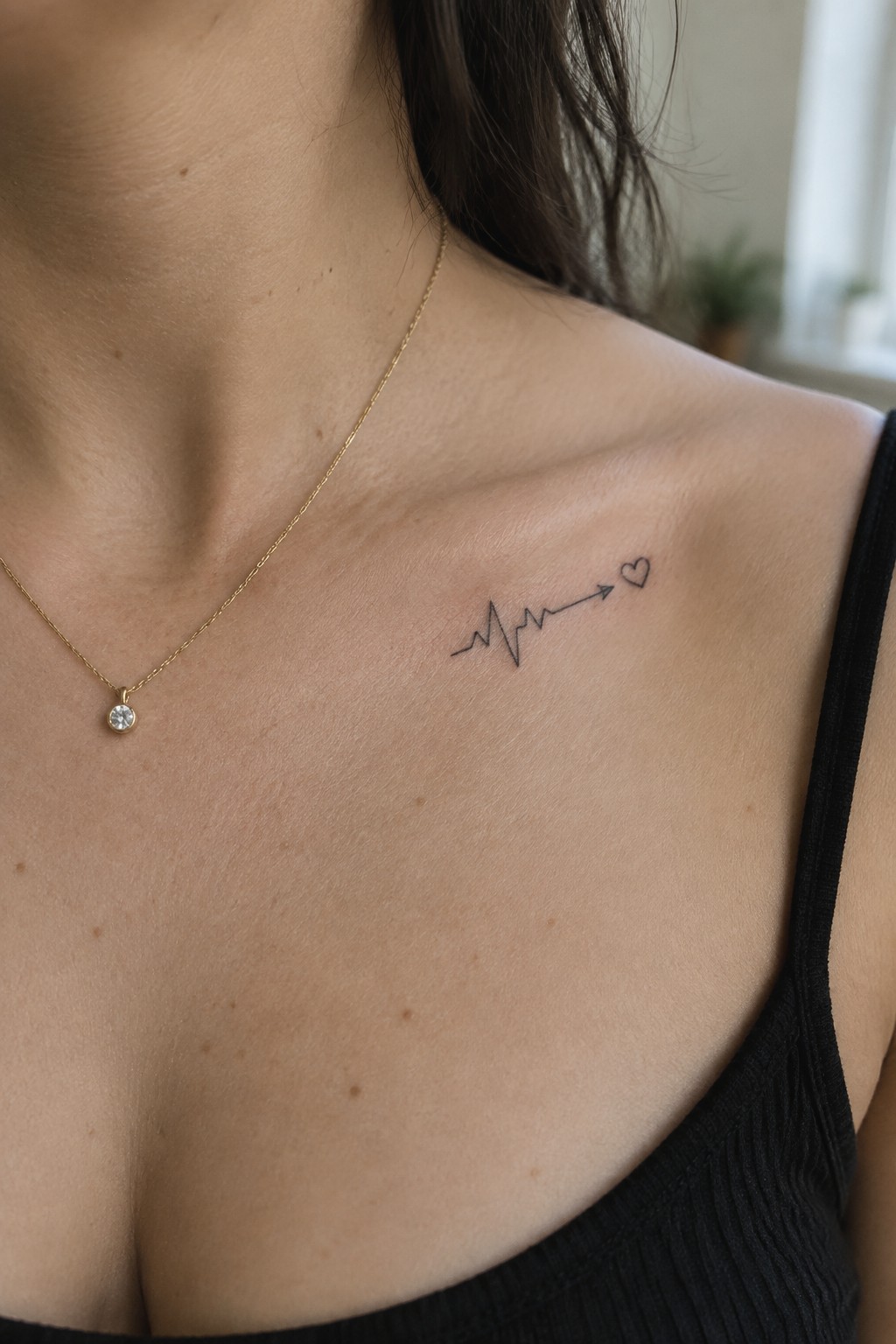 Fine line heartbeat tattoo with arrow and heart on a woman's upper chest near the collarbone