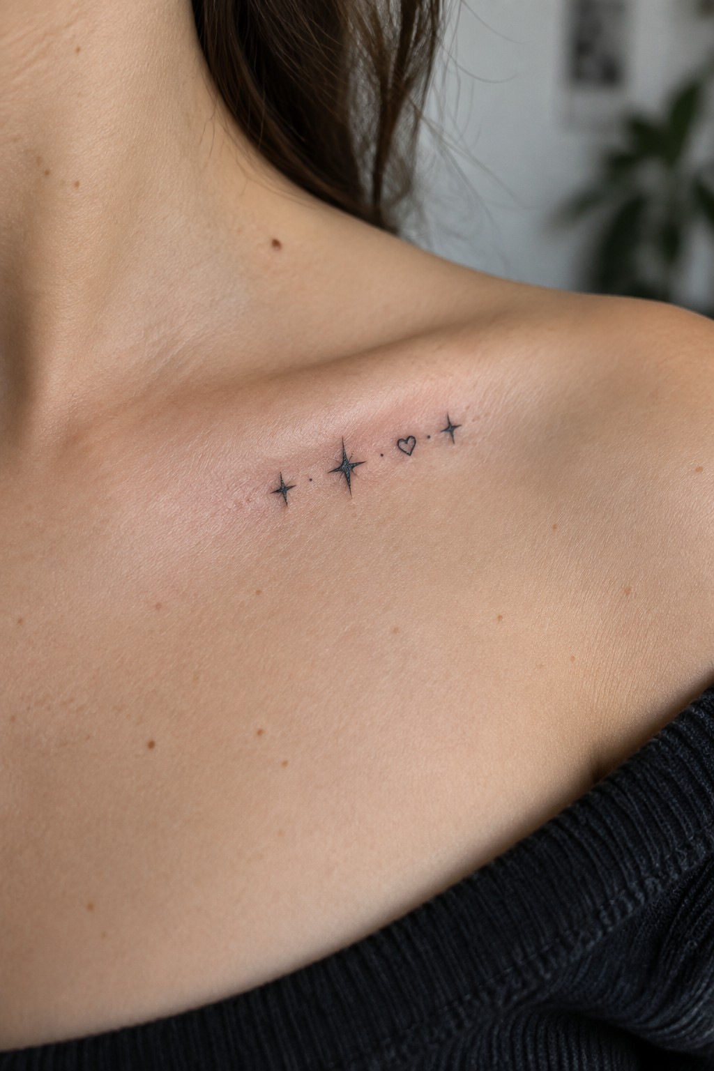 Black tattoo of stars, dots, and heart on light-skinned shoulder.