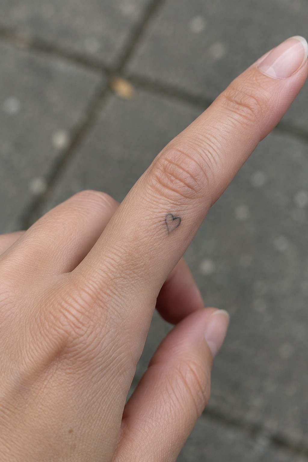 Small fine line heart tattoo on the side of a finger