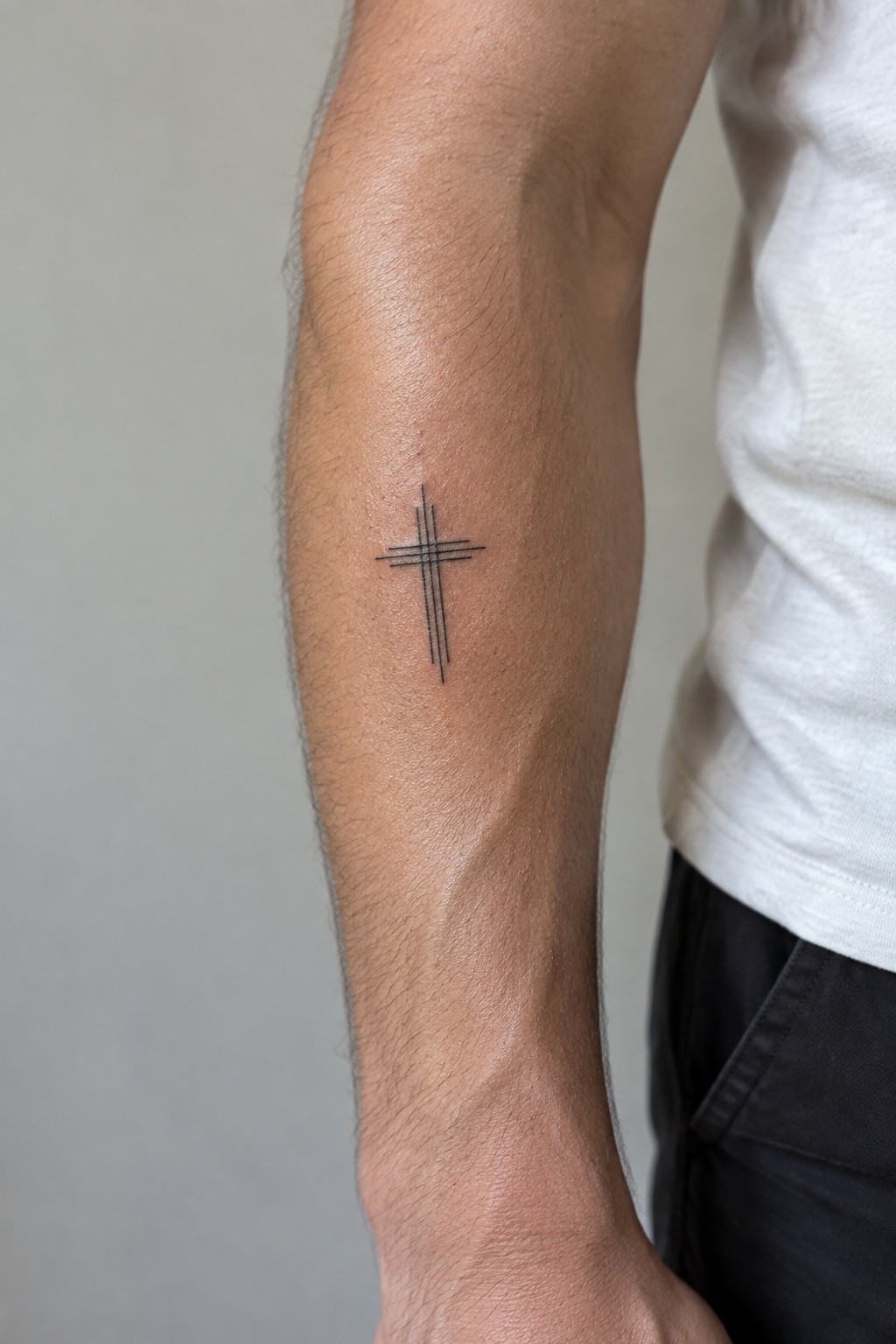 Hairy forearm in white t-shirt with black multi-lined cross tattoo on skin