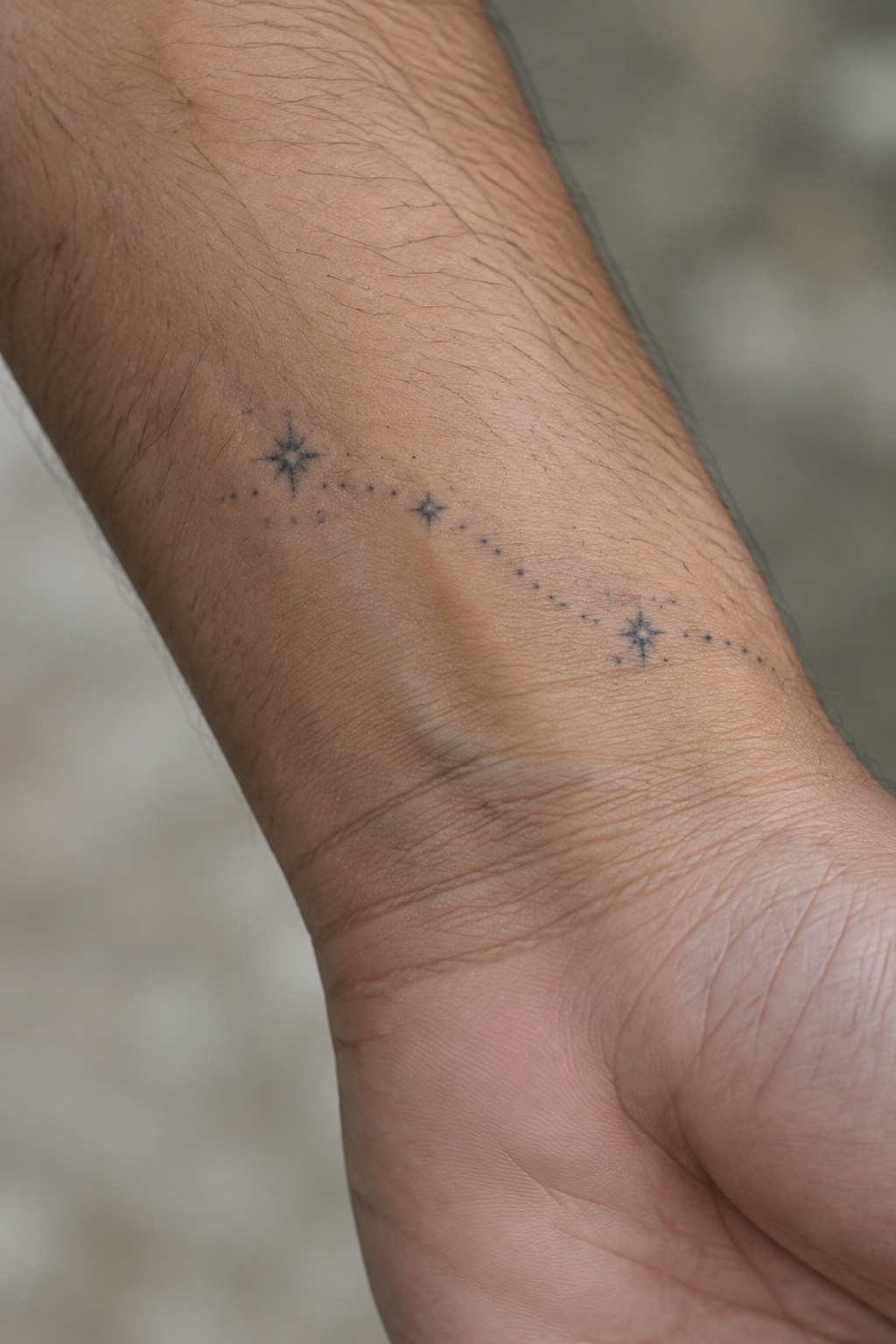 Hairy forearm with constellation tattoo of stars linked by dotted lines.