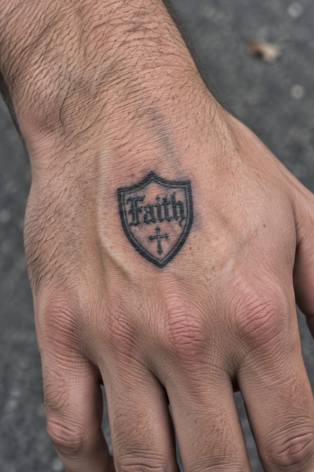 Man's hand showing black shield tattoo with
