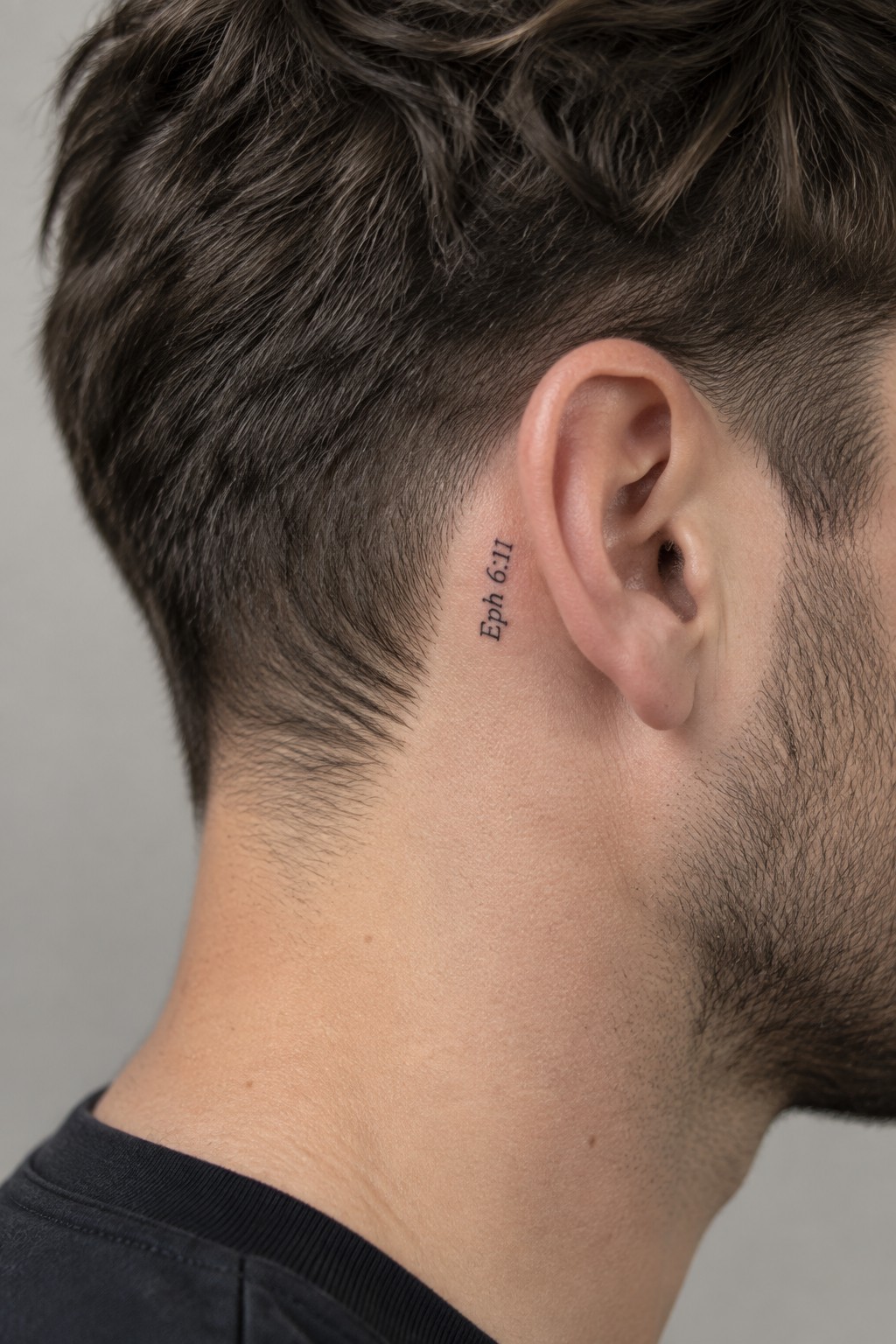 Close up of a small Eph 6:11 tattoo behind a man's ear on the side of the neck
