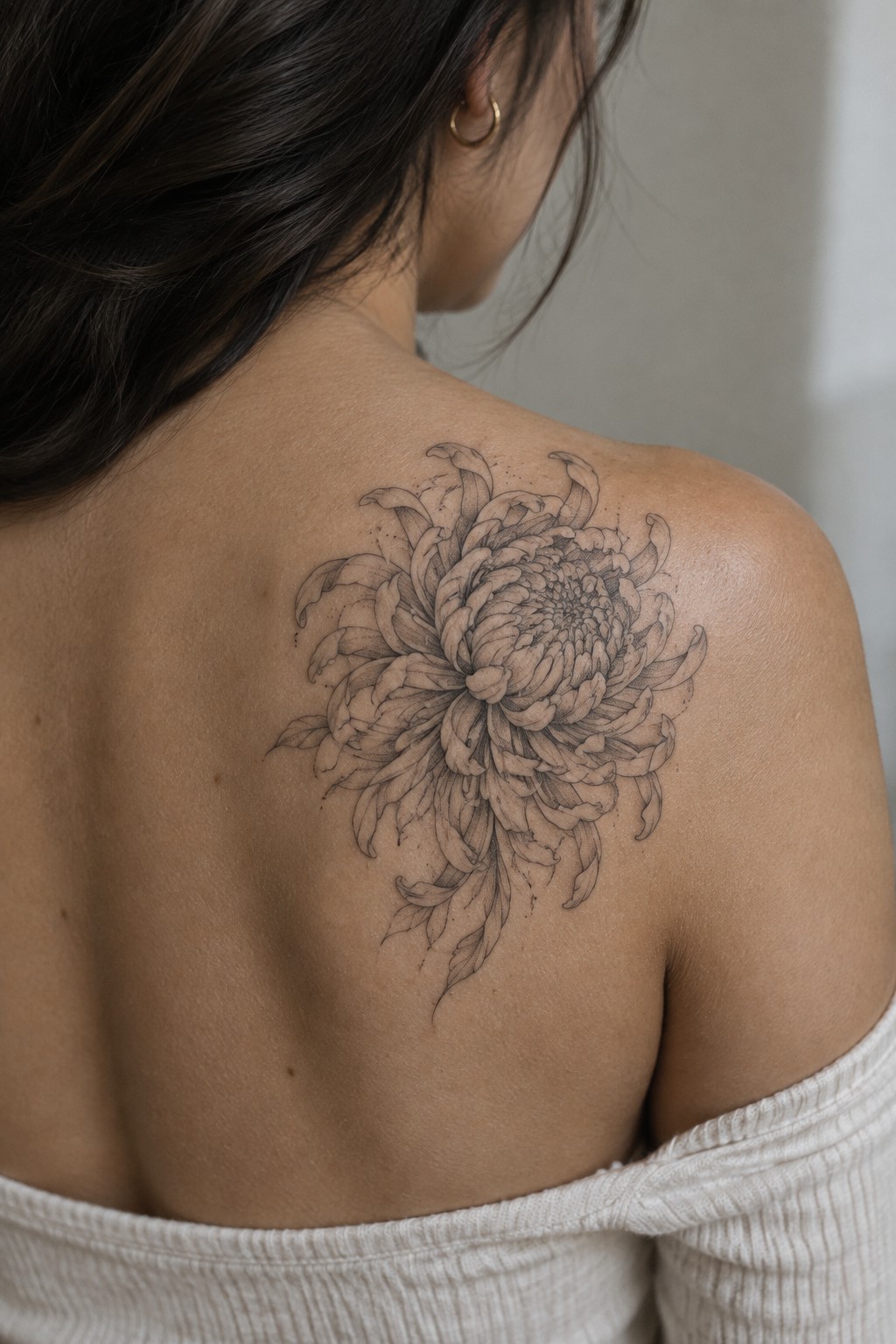 Fine line chrysanthemum tattoo placed on a woman's upper back and shoulder