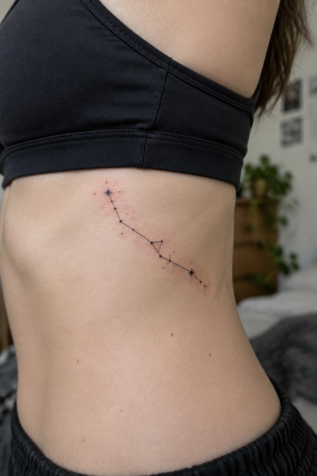 Constellation tattoo with stars and lines on side torso under black crop top