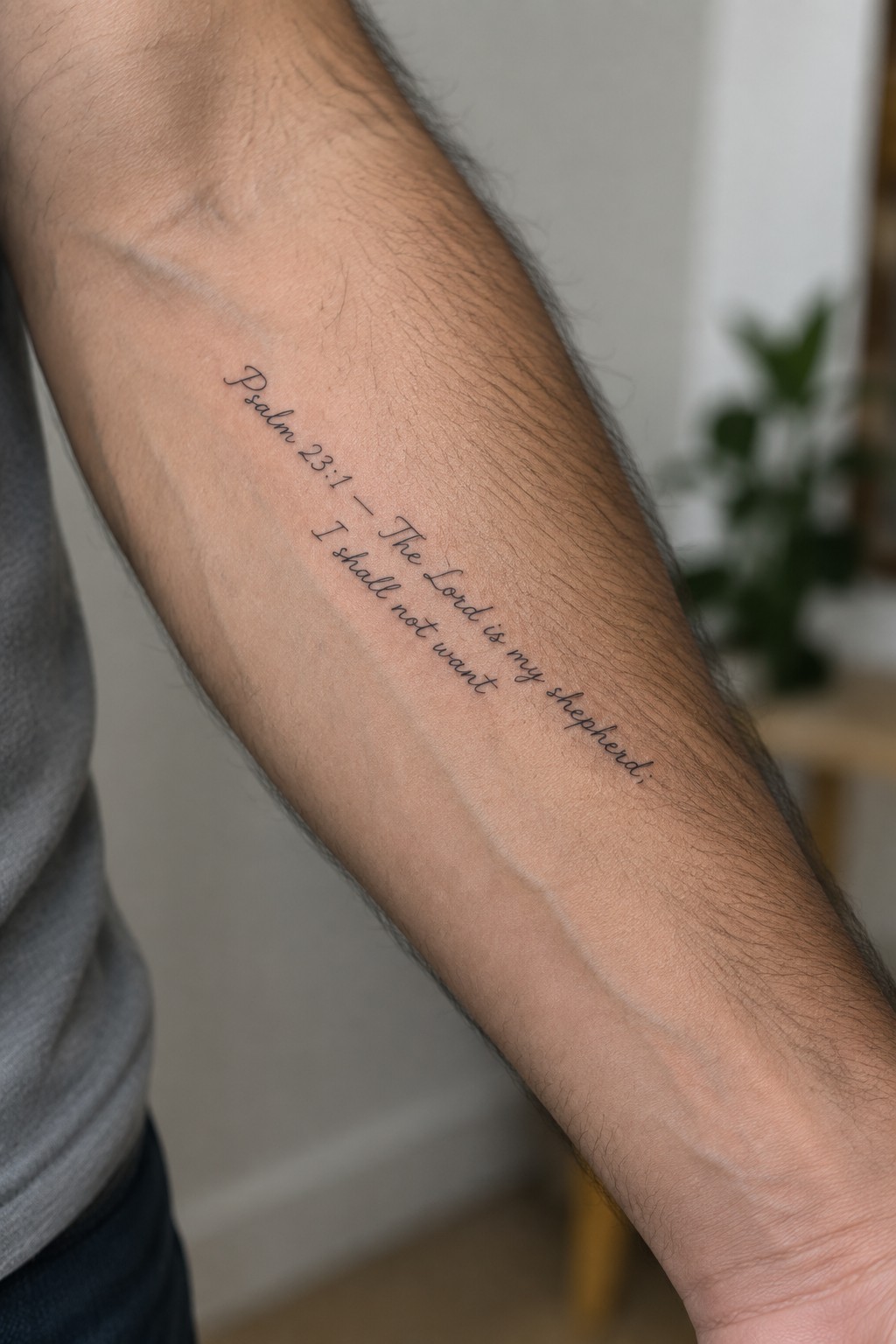 Hairy forearm with cursive black tattoo of Psalm 23:1 Bible verse
