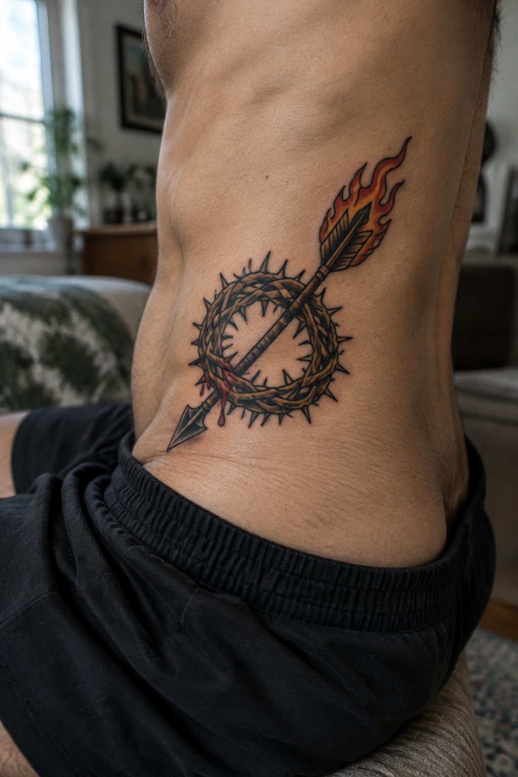 Crown of thorns tattoo pierced by a flaming arrow on the side of a man's torso with blood details.