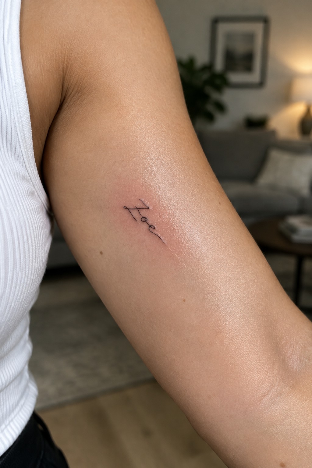 Fine line tattoo of the name Kate written in a loose handwritten cursive style on the upper arm.