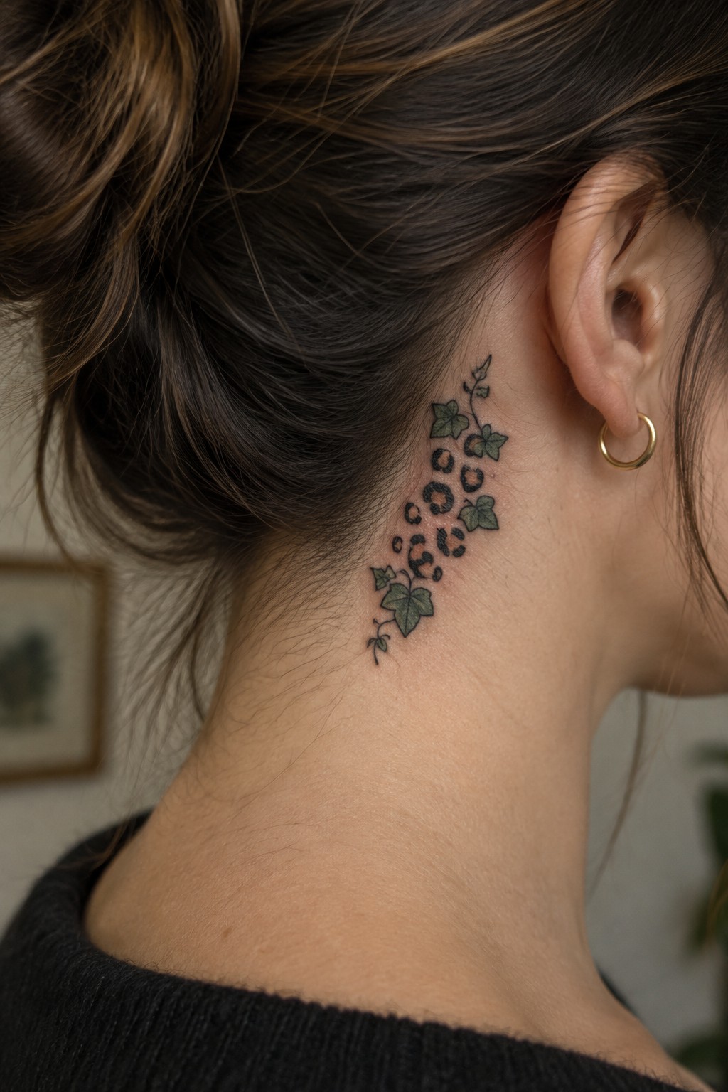 Woman's neck tattoo with green ivy leaves and leopard spots, hair in bun, gold earring