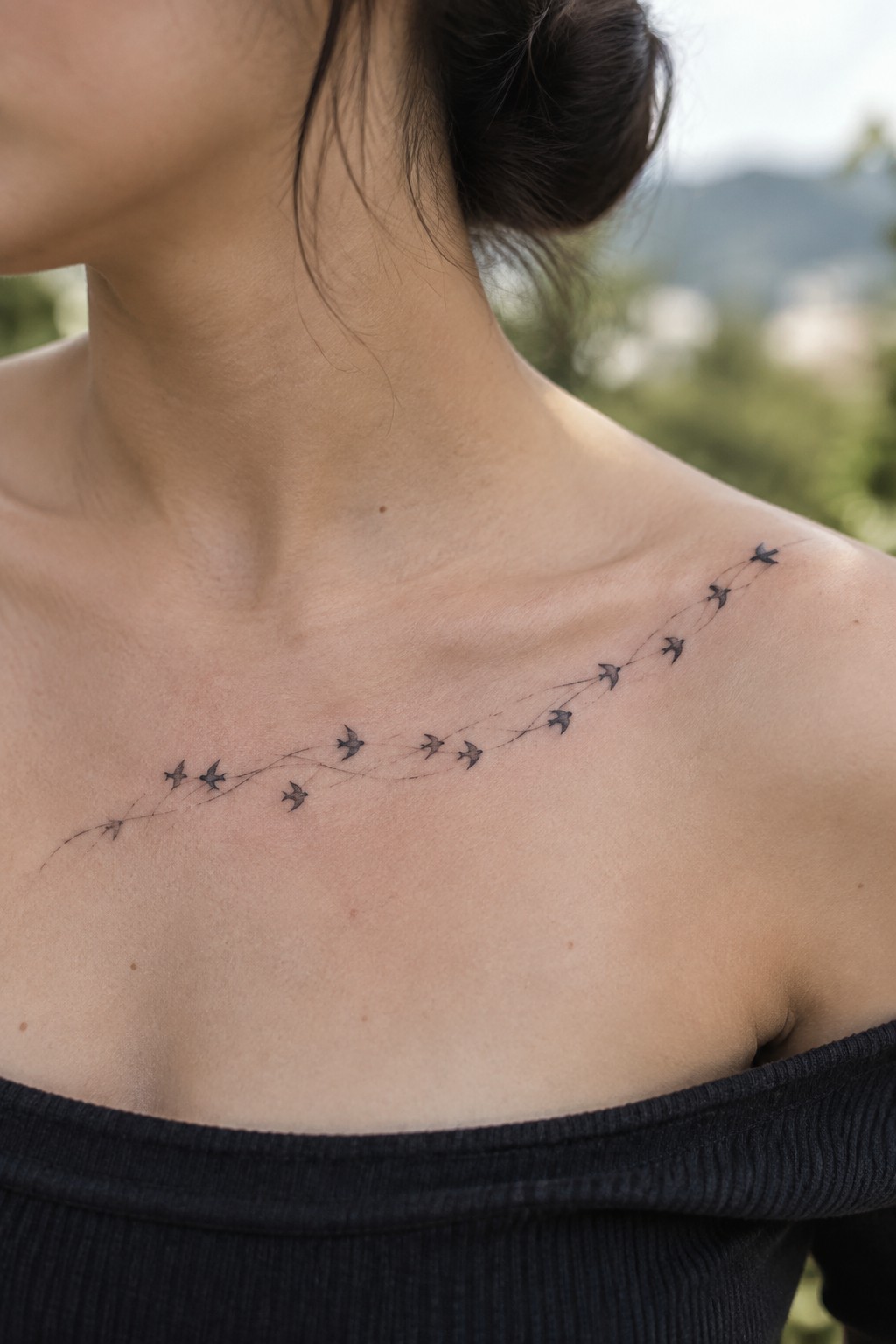 Flock of birds tattoo with dotted lines across shoulder above black off-shoulder top