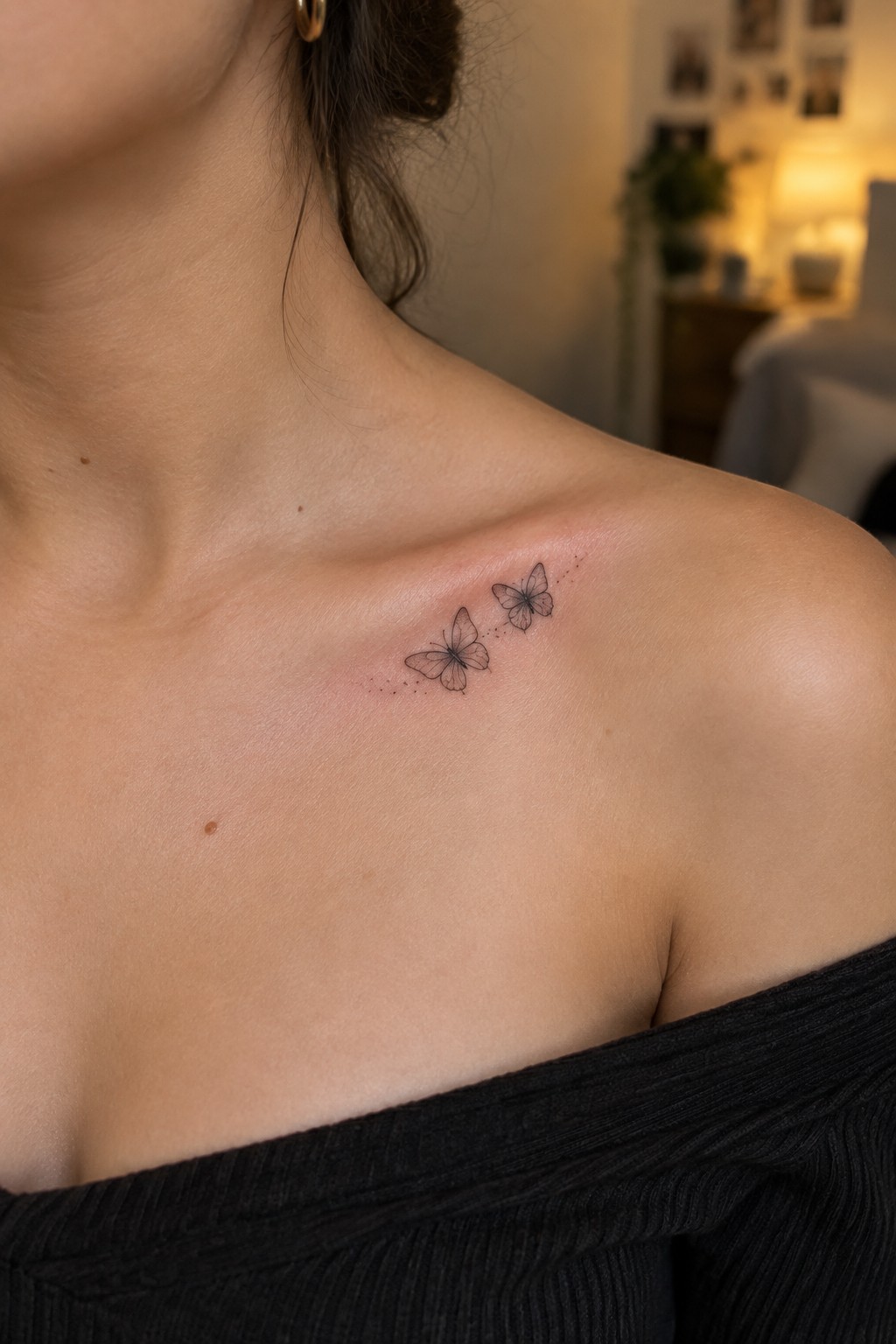 Shoulder with two black butterfly tattoos above black off-shoulder top, skin slightly red.
