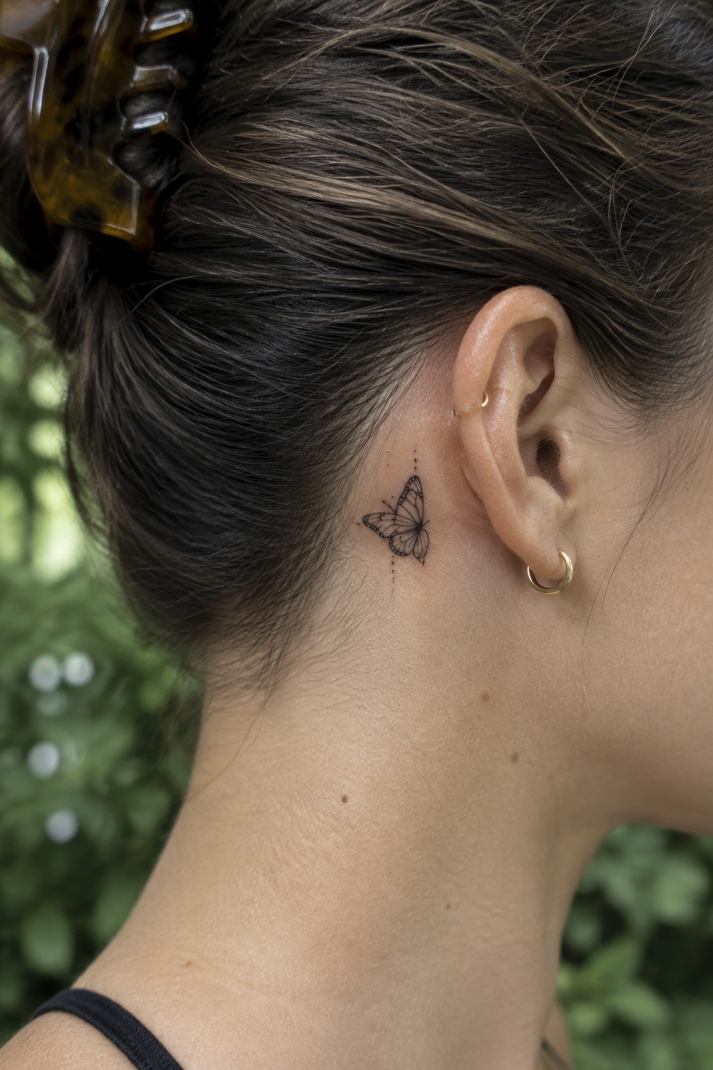 Butterfly tattoo behind ear on neck with gold hoops and tortoiseshell hair clip