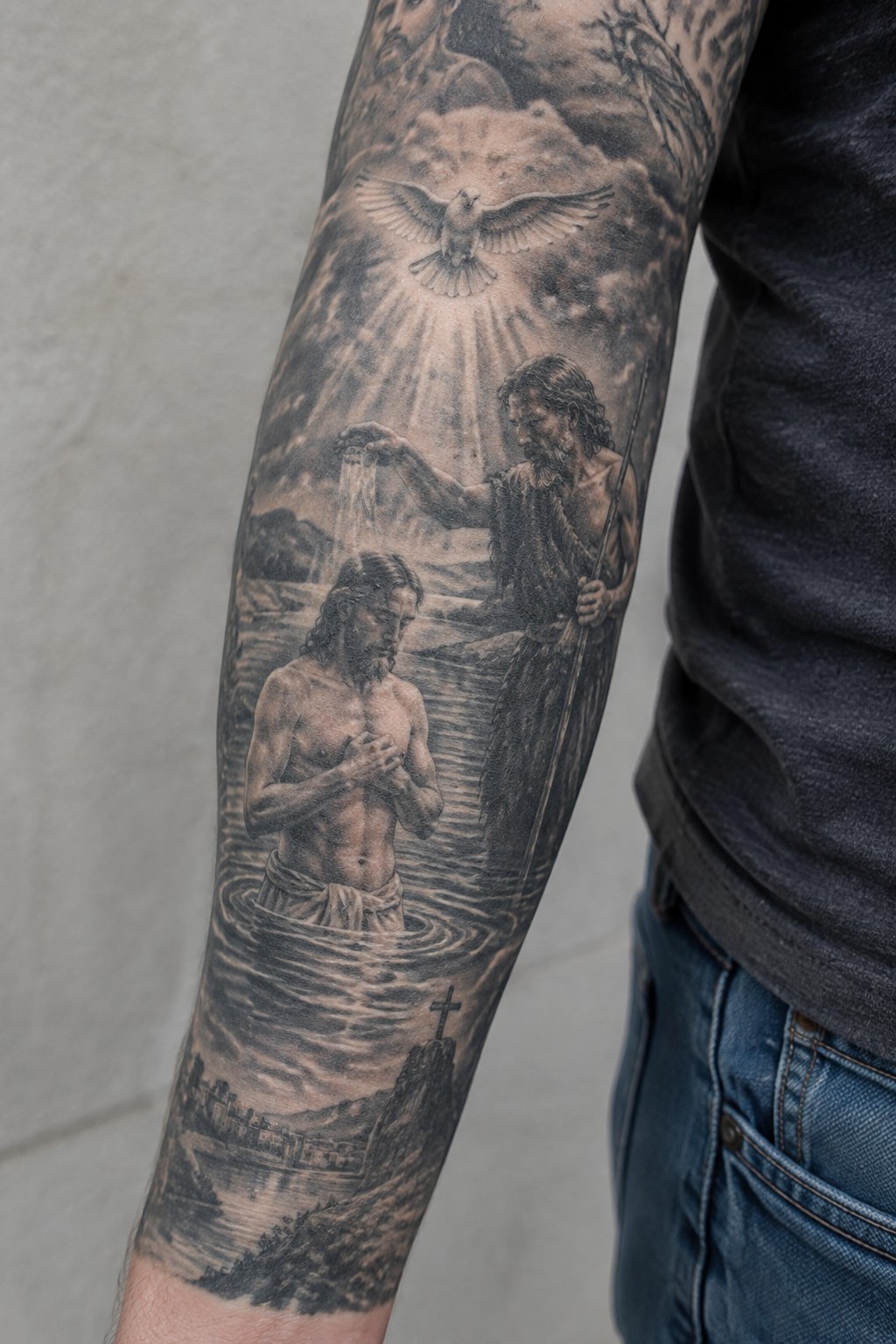 Black and gray realistic sleeve tattoo of the baptism of Jesus with John the Baptist pouring water, a dove above, and a cross on a rock at the bottom.