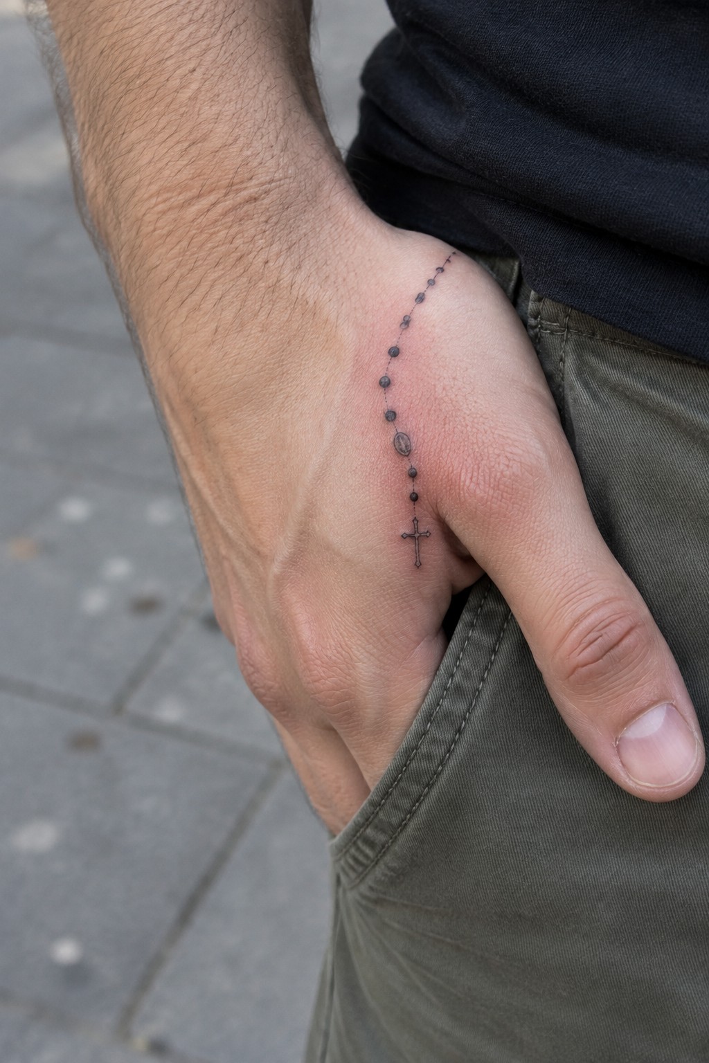 Rosary bead tattoo with cross on hand in olive green pocket