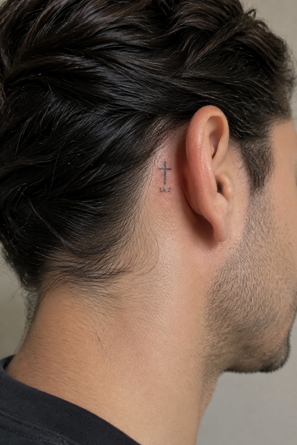 Dark-haired man's head with small cross tattoo and