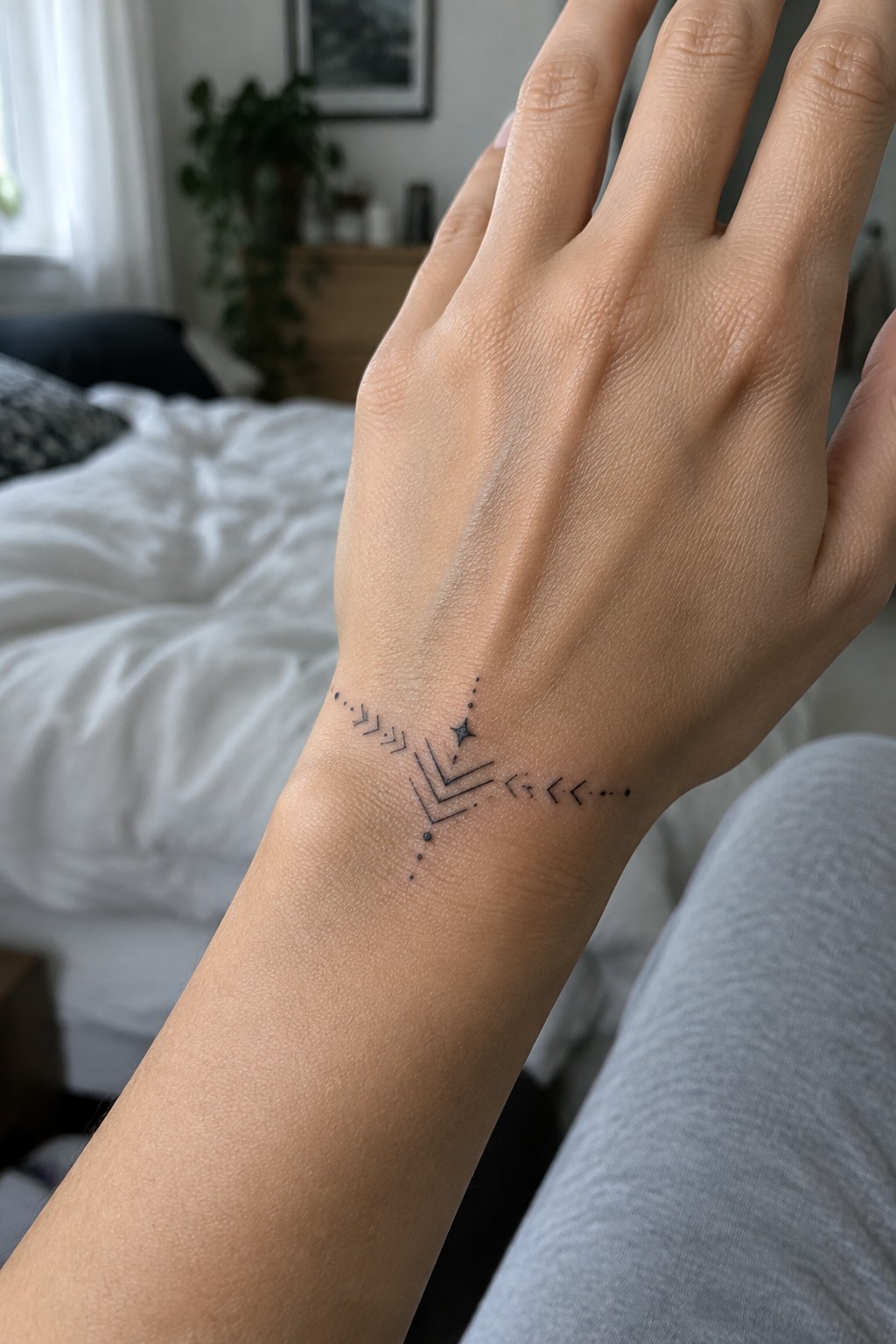 Wrist with black geometric tattoo of chevrons, dots, and star