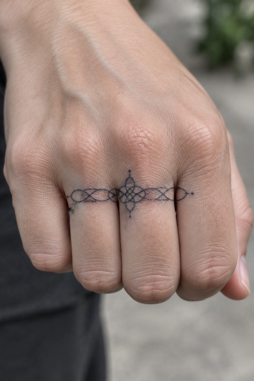 Clenched fist with intricate black Celtic knot tattoo spanning across the fingers.