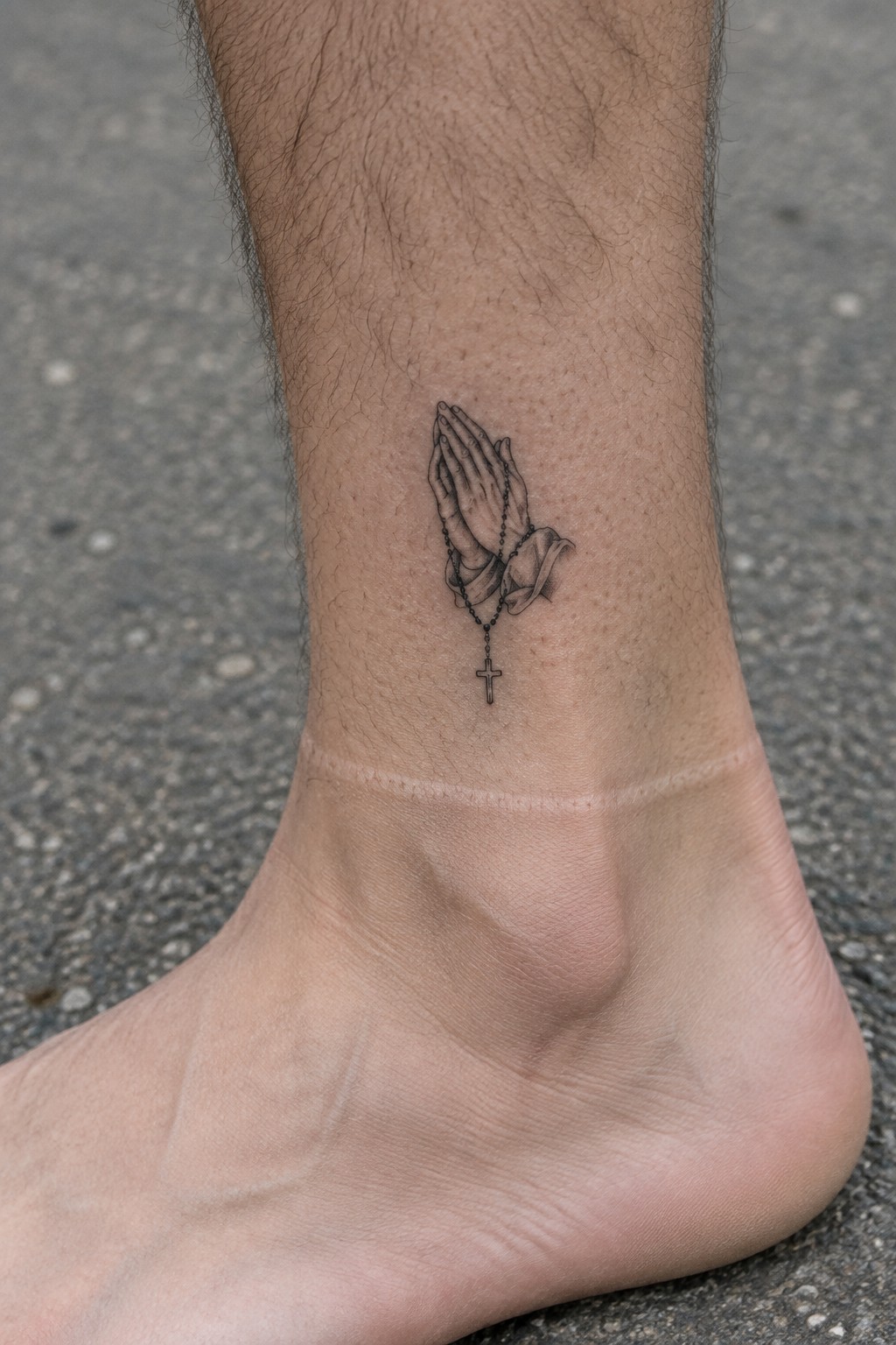 Realistic black and grey praying hands with rosary cross tattoo on ankle