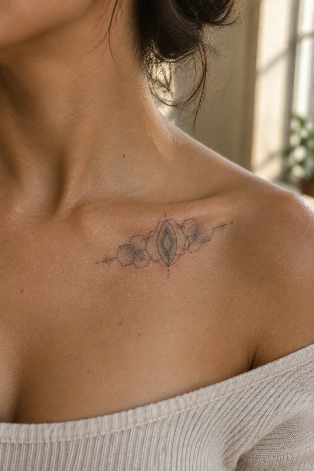 Fine line geometric tattoo of linked hexagons with a central leaf shape placed across the collarbone on light skin.