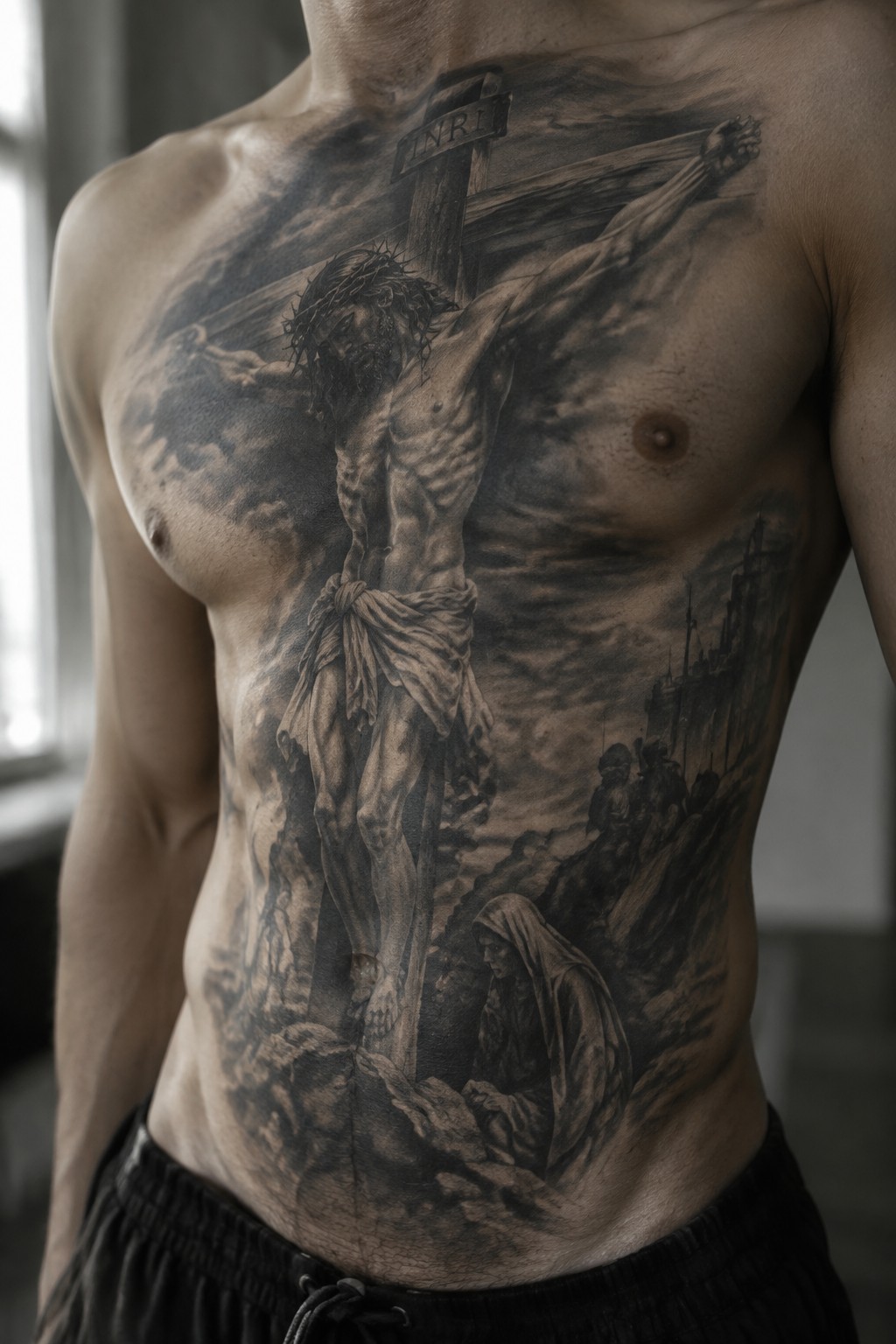 Muscular torso with large black-and-gray tattoo of Jesus crucified on cross.