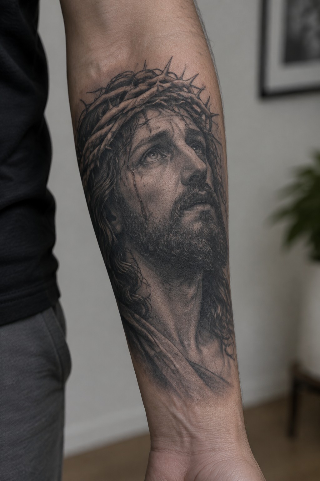 Realistic black-and-gray tattoo of Jesus with crown of thorns on forearm