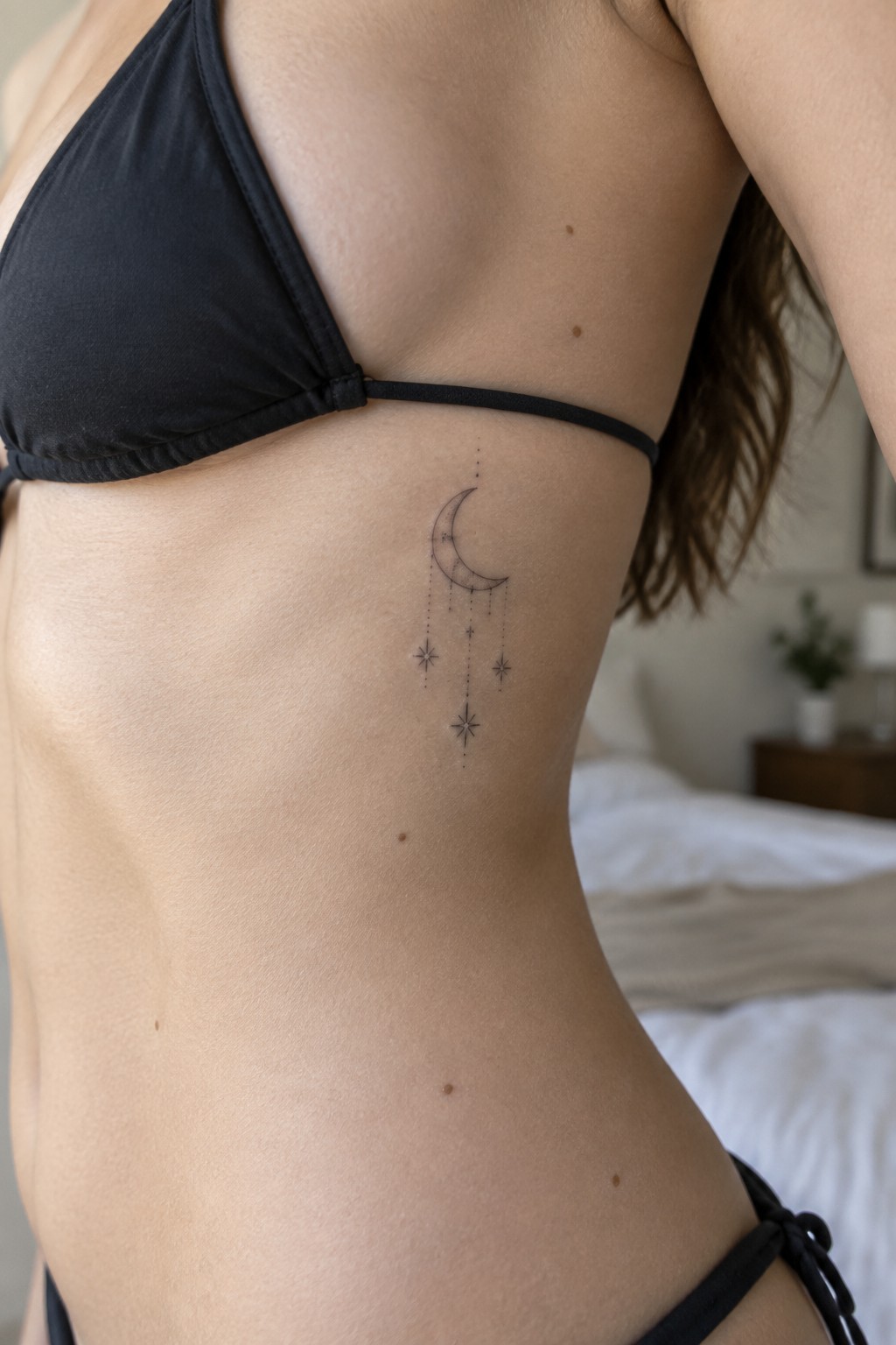 Woman in black bikini with crescent moon and stars tattoo on ribs