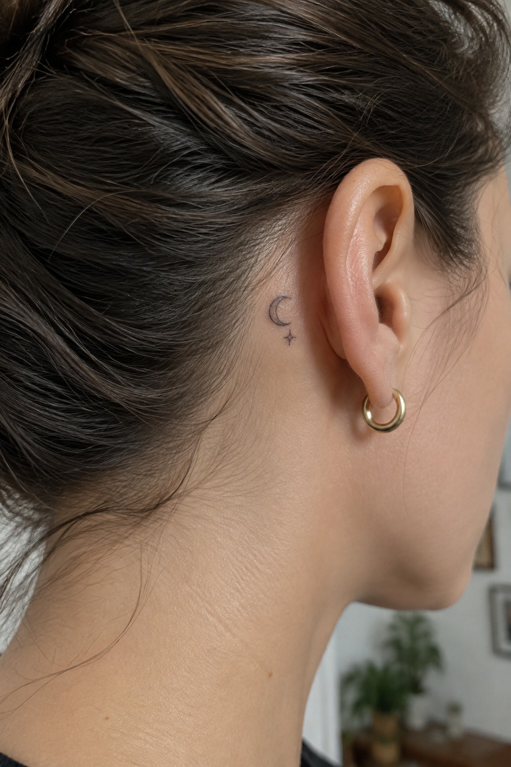 Small crescent moon and star tattoo behind ear with gold hoop earring