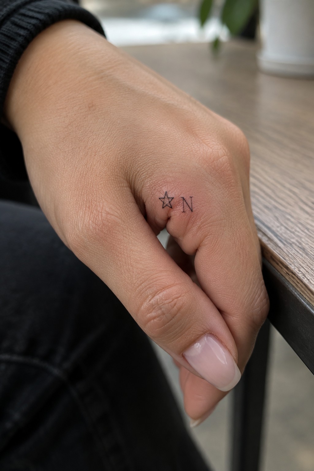 Fine line star and initial tattoo on the side of a ring finger