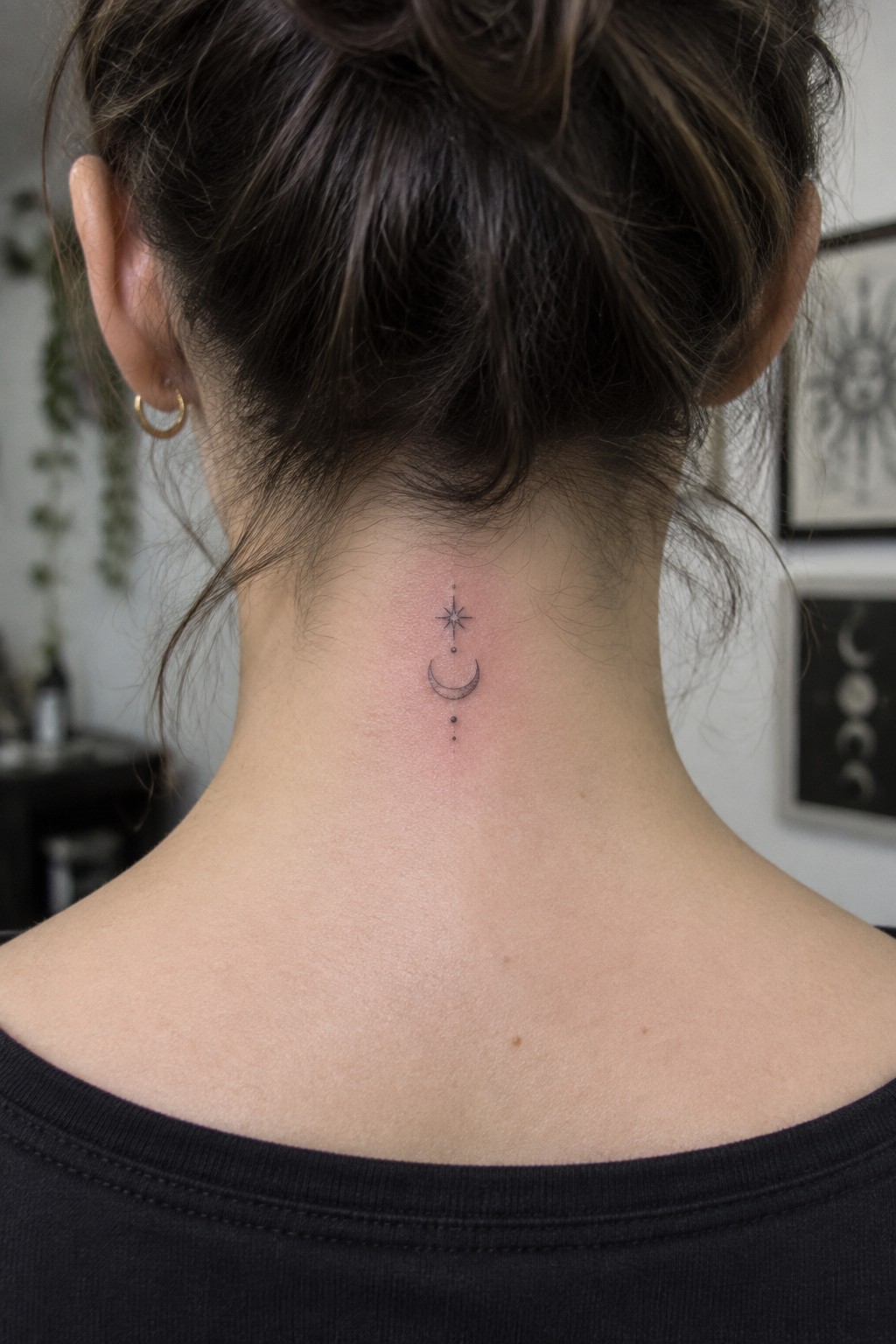Woman's neck with crescent moon and star tattoo, dark bun, black top